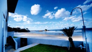 A coastal view from a building with a concrete balcony overlooking a beach and ocean. - Indigo Geohouse DS1 (Iwami)
