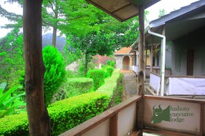 A lush garden with a wooden fence, a stone pathway, and a building with a sign reading "lushoto executive lodge". - Lushoto Executive Lodge (Lushoto)
