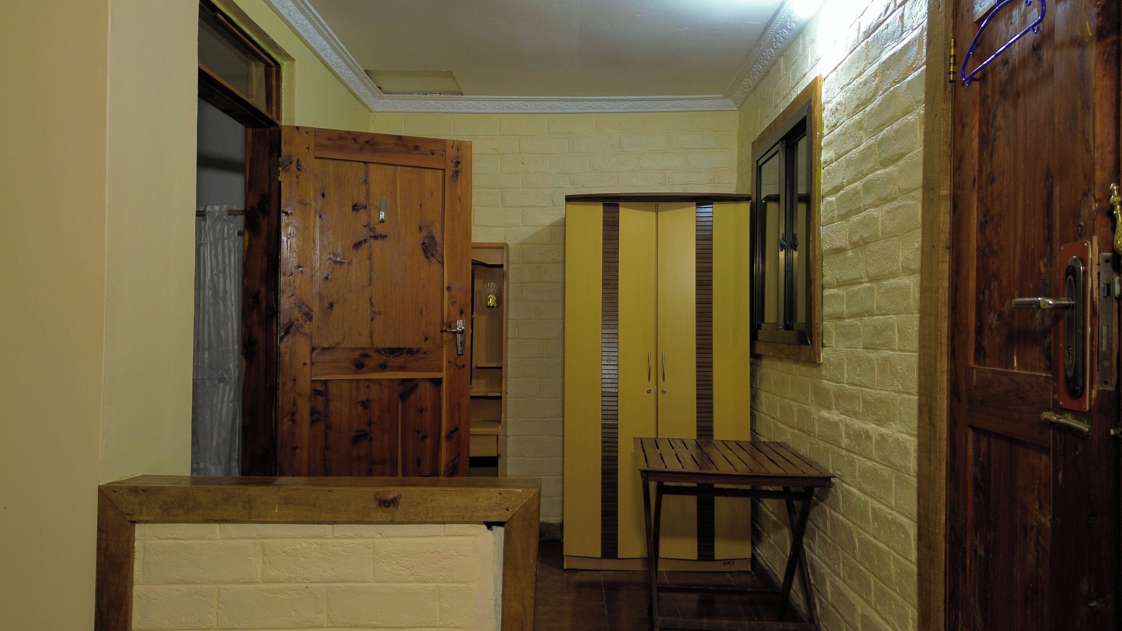 A hallway with a wooden door, a yellow cabinet, and a small table.
