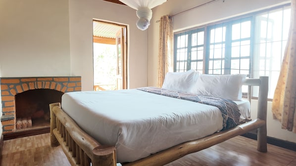 A room with a bed, a fireplace, and large windows.