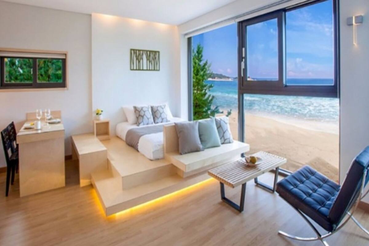 A modern living room with a sofa, coffee table, and a view of the beach.