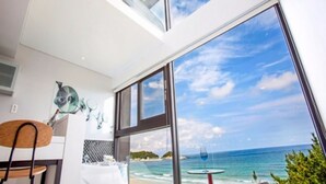 Habitación moderna con un amplio ventanal que ofrece vista al mar y a la playa.