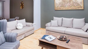 A living room with two sofas, a coffee table, and a wall-mounted painting. - The Muses House (Athens)
