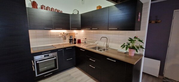 A modern kitchen with dark cabinetry, a stainless steel sink, and a built-in oven.