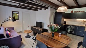A modern living room with a wooden dining table, purple sofa, and a black floor lamp.