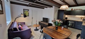 A modern living room with a wooden dining table, purple sofa, and a black floor lamp.