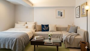 A modern, well-lit bedroom with two beds, a coffee table with books, and a vase with flowers. - Rc Annex 2 (Tokyo)