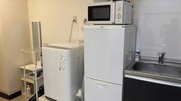 Una cocina compacta con microondas, cafetera y lavabo.