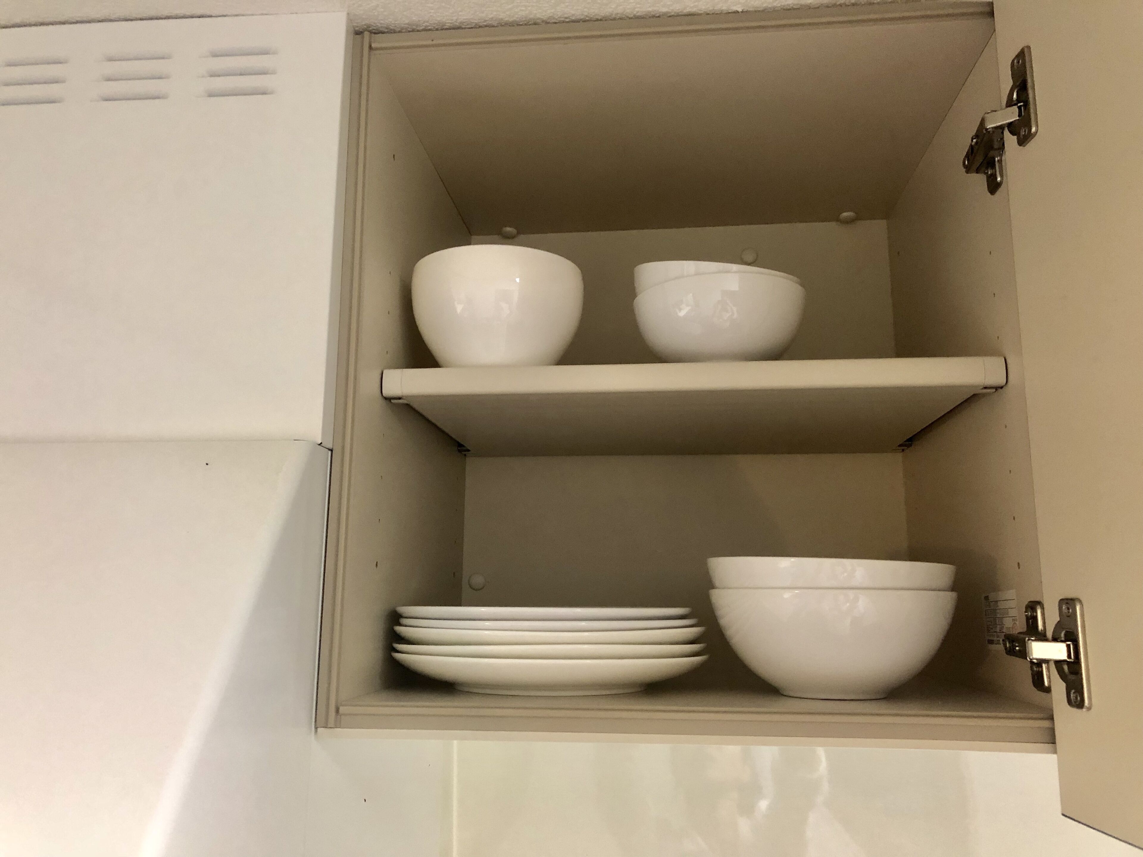 Un armario de cocina con dos estantes, cada uno con cuencos y platos.