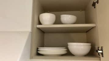 Un armario de cocina con dos estantes, cada uno con cuencos y platos.
