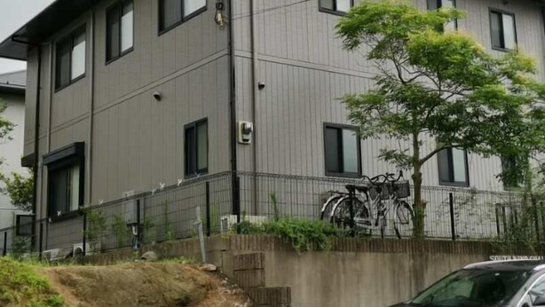 En byggnad med flera våningar, en grå fasad, många fönster och en cykel parkerad utanför.