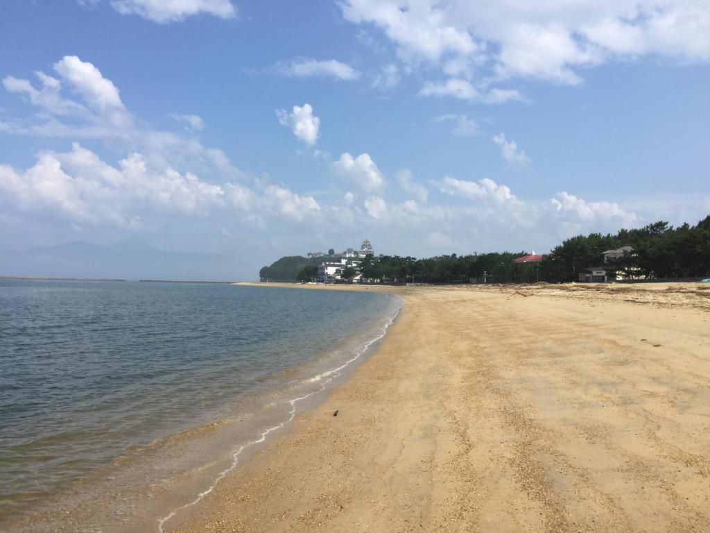 A beach with a clear sky and a distant building.