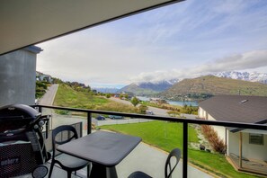 Enjoy breathtaking views of the surrounding mountains and water from this balcony, complete with a table, chairs, and barbecue grill.