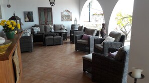 Relax in a stylish lounge area with wicker sofas and armchairs, surrounded by decorative elements and natural views.