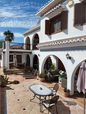 Relax on the villa's spacious patio, surrounded by lush plants and a small pool.