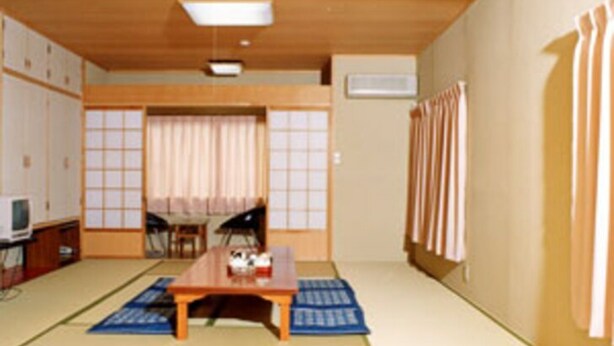 A traditional Japanese room with tatami flooring, a low table, a television, and sliding doors. - Hotel Shirahama (Shirahama)