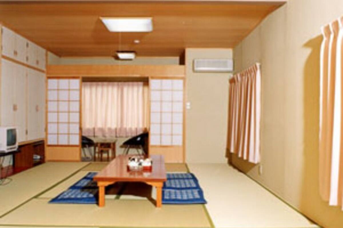 A traditional Japanese room with tatami flooring, a low table, a television, and sliding doors.