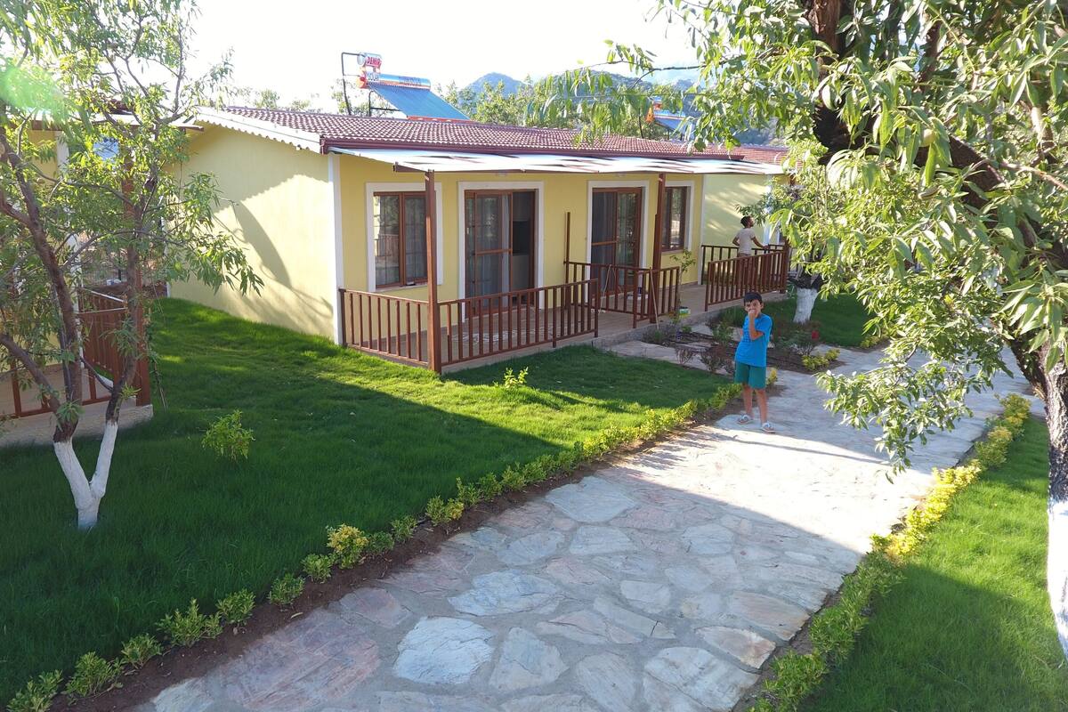A yellow building with a tiled roof, a stone pathway, and a small garden area.