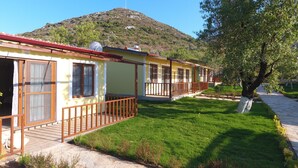 Una hilera de casas amarillas con balcones de madera y antenas parabólicas, frente a una colina con vegetación escasa.