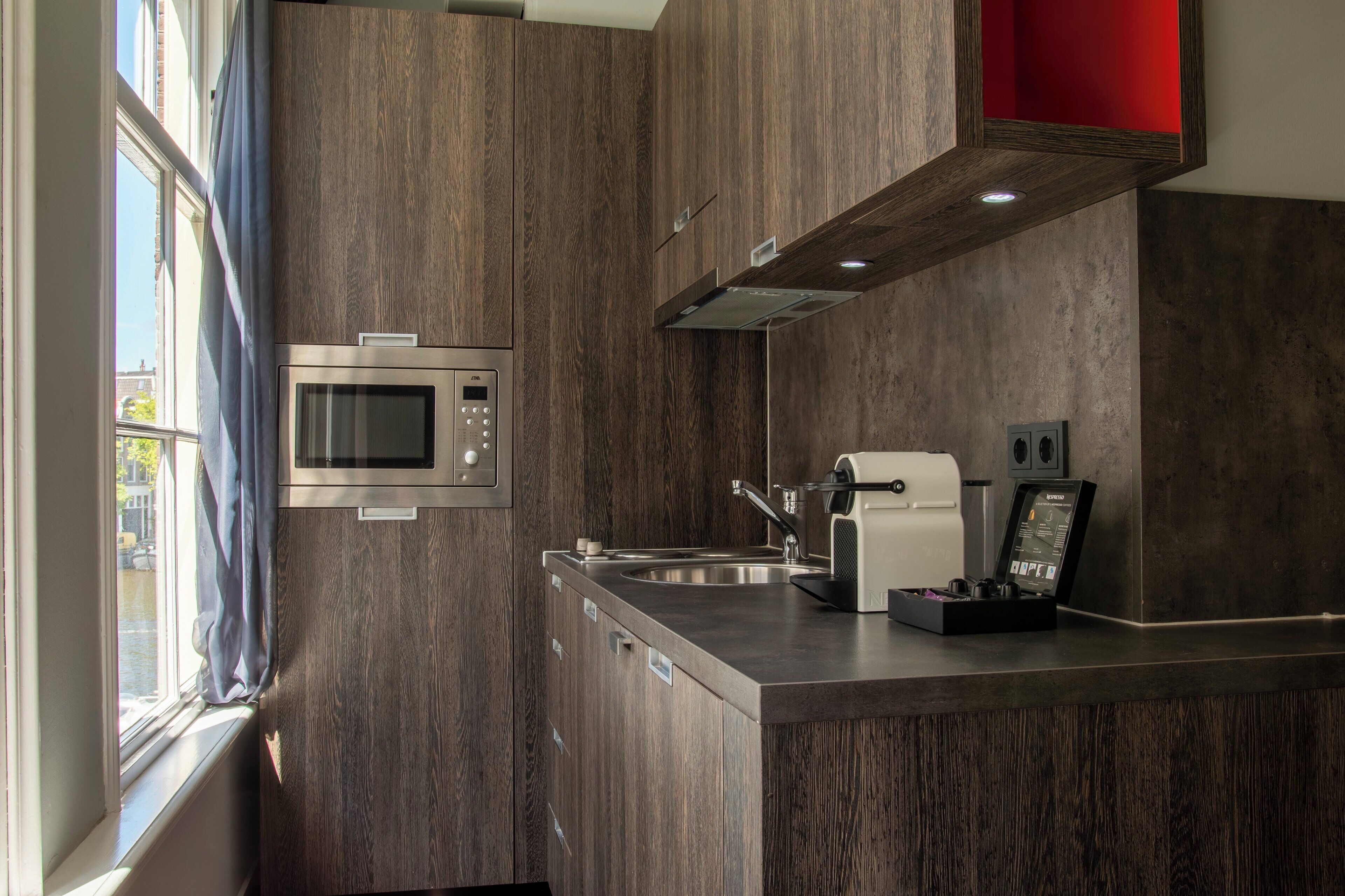 A modern kitchen with a built-in microwave, coffee maker, and a sink.