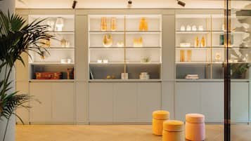 A modern interior with a wooden floor, grey cabinets, and orange stools.