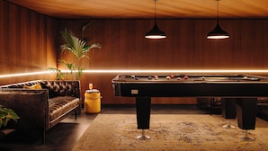 A pool table with balls, a sofa, and pendant lighting in a room with wooden walls and a ceiling. - Leonardo Eden Hotel Amsterdam City Center (Amsterdam)