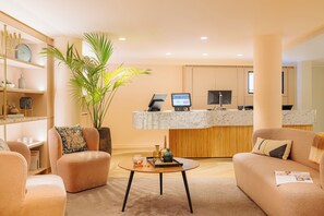 A modern living room with a sofa, armchair, coffee table, and a large plant. - Leonardo Eden Hotel Amsterdam City Center (Amsterdam)