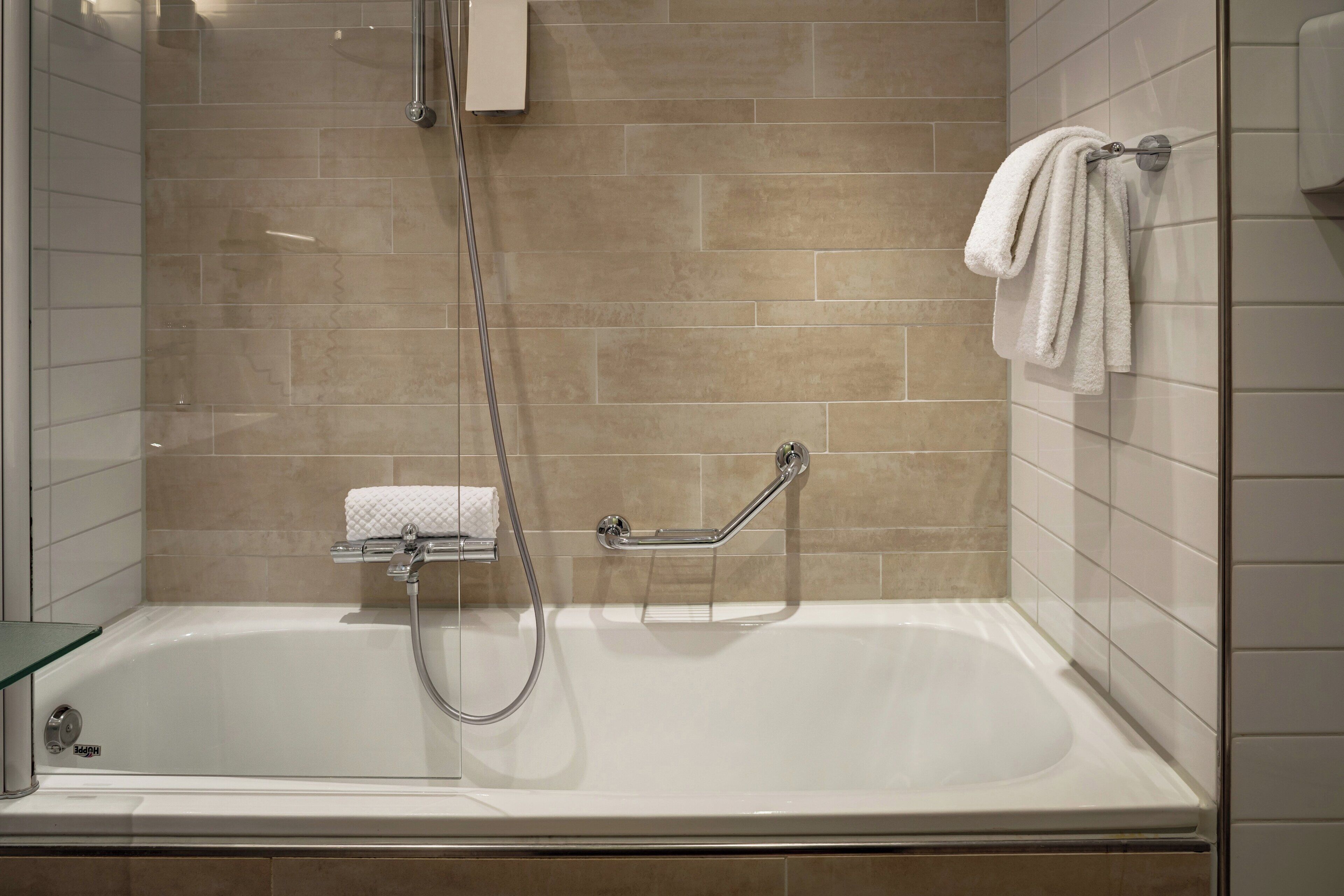 Un baño moderno con bañera, cabina de ducha de vidrio y un perchero para toallas.