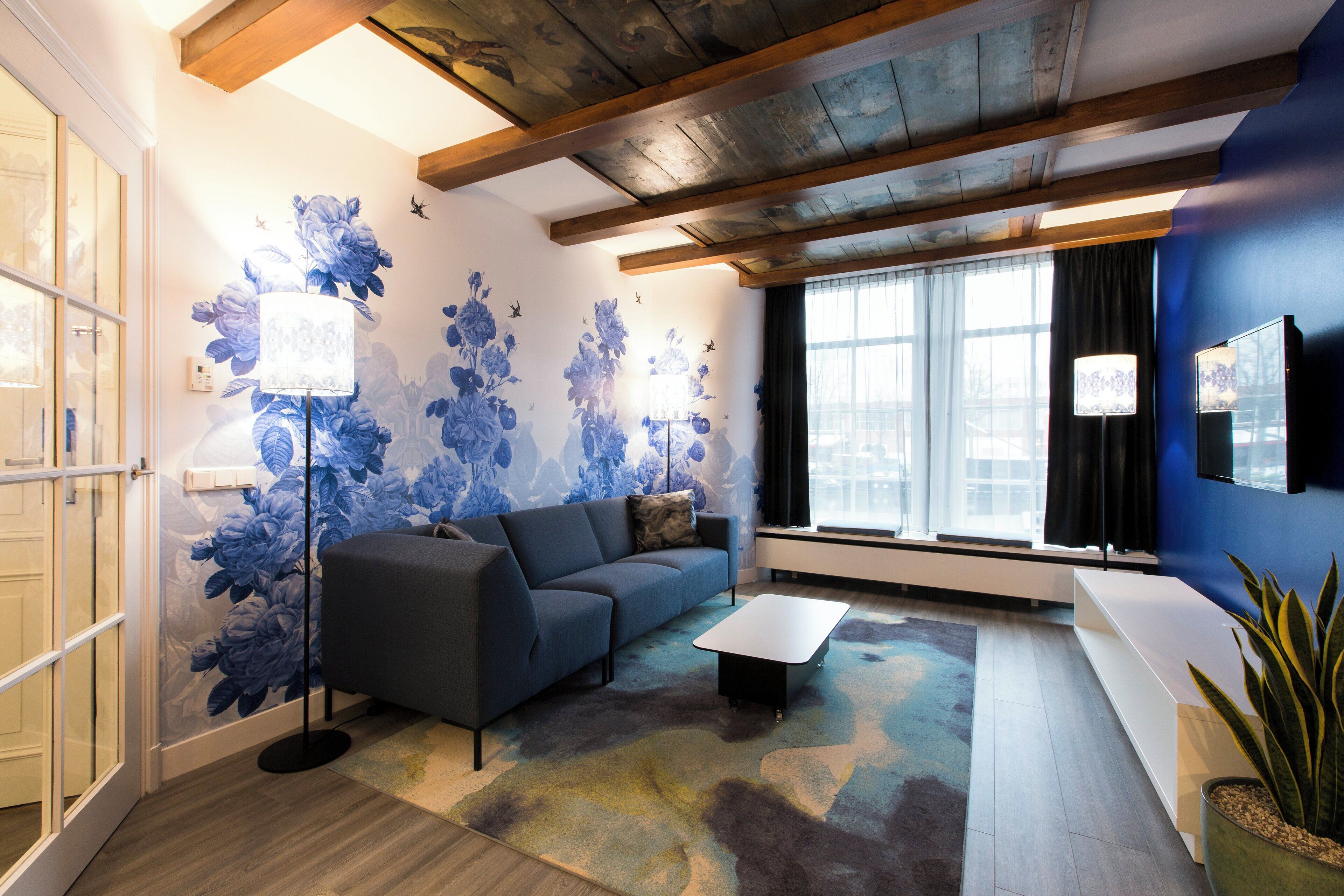 Un salon moderne avec un canapé, une table basse et une grande fenêtre agrémentée de rideaux.