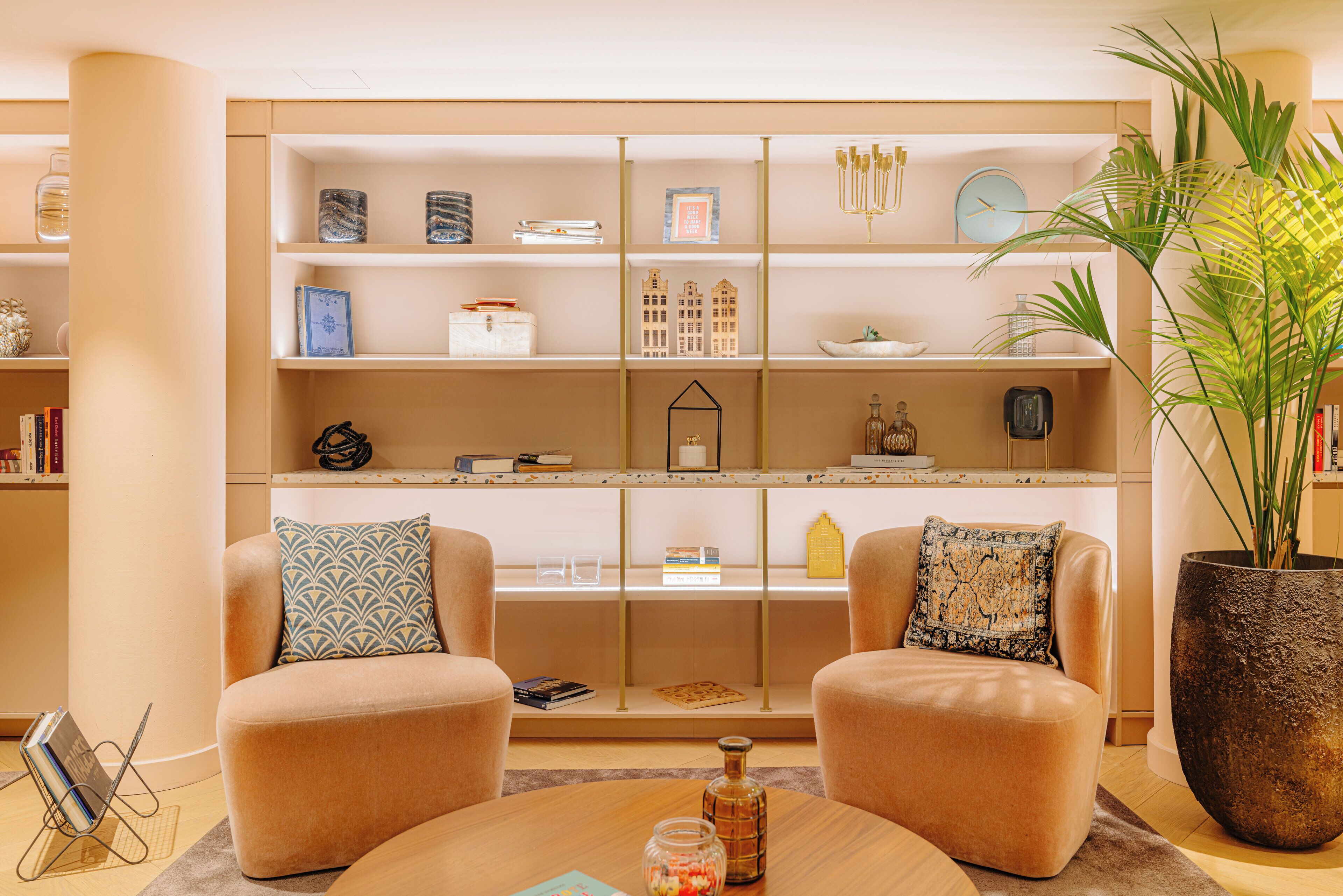 A modern living room with a beige sofa set, a round coffee table, and a large potted plant.