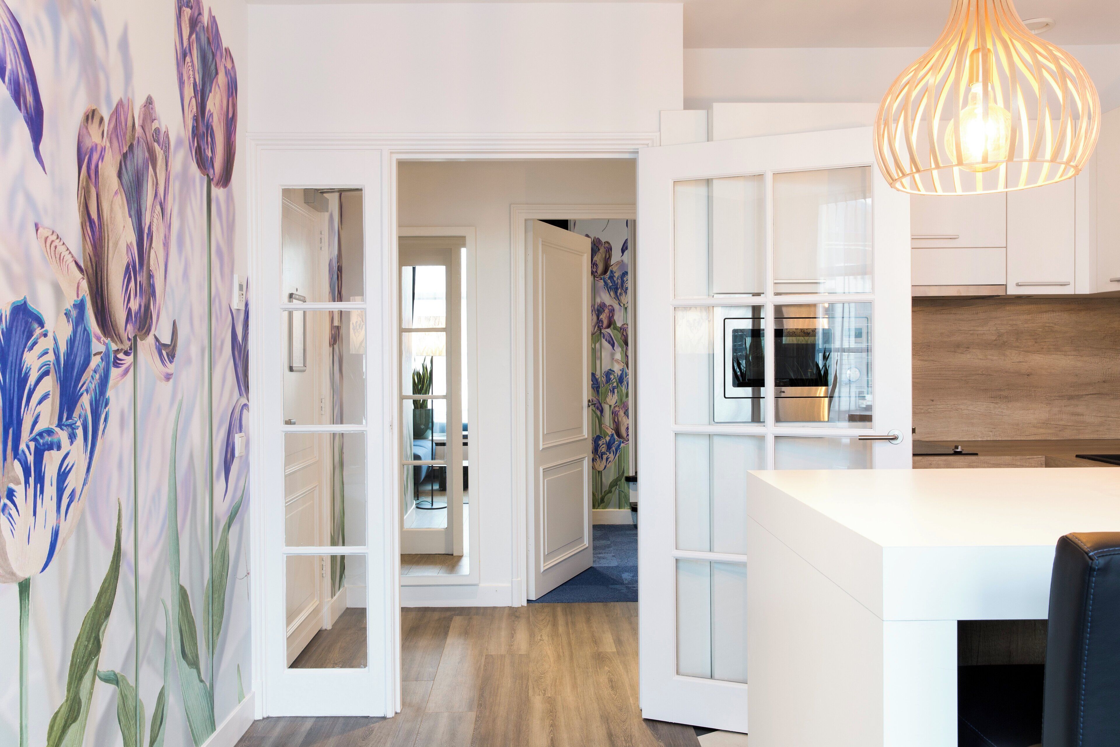 Een moderne keuken met witte kastjes, een houten aanrechtblad en een hangende pendantlamp.