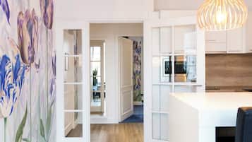 Een moderne keuken met witte kastjes, een houten aanrechtblad en een hangende pendantlamp.