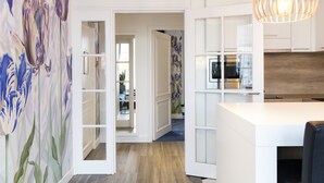 A modern kitchen with white cabinetry, a wooden countertop, and a hanging pendant light. - Leonardo Eden Hotel Amsterdam City Center (Amsterdam)