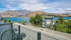 Un espace de stationnement offrant une vue sur la montagne, donnant sur un plan d’eau, et à proximité d’un bâtiment équipé d’une antenne parabolique.