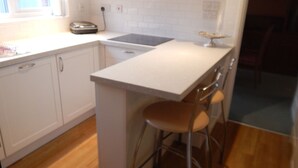 A kitchen with white cabinets, a countertop, a stove, and a small bar area with stools. - Cherry Palace 3 BD Parking Spaces groups (Cambridge)