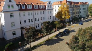 Eine Reihe weißer Häuser mit roten Ziegeldächern, eine gepflasterte Straße und parkende Autos.