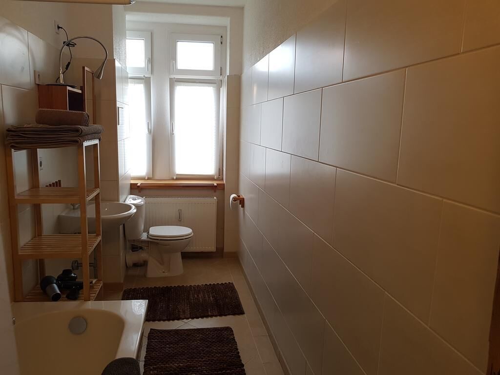 Ett litet badrum med toalett, handfat och hyllor.