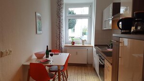 Eine kleine Küche mit Esstisch, Stühlen und einem Fenster mit Vorhängen.