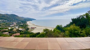 Vista costera desde una terraza, con cielo despejado y una playa arenosa en la distancia.