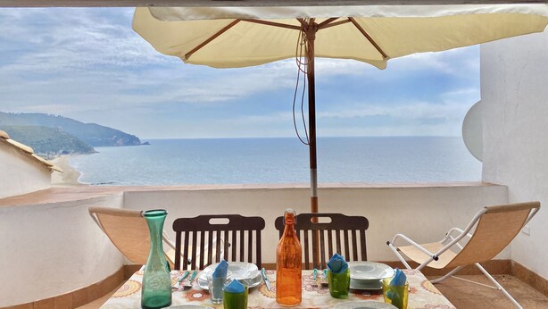 Mesa para dos con vista al mar, una playa y un paisaje montañoso.