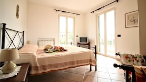 Un dormitorio con cama, mesita de noche, lámpara y televisor.
