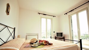 Un dormitorio con cama, televisión y vistas al balcón.