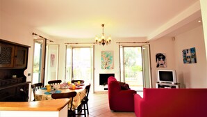 Un comedor con una mesa preparada para cuatro personas, un sofá rojo y un televisor en una sala de estar.