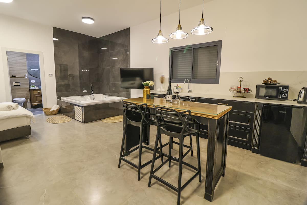 A modern kitchen with a central island, bar stools, a built-in oven, and a TV mounted on the wall.