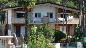 A two-story building with a balcony on the upper floor, a gated entrance, and a small garden area. - Villa Anny apartment 1 (Lignano Sabbiadoro)