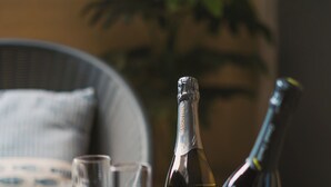 Un tavolo con una bottiglia di champagne e due bicchieri su un sottopiatti di vimini.
