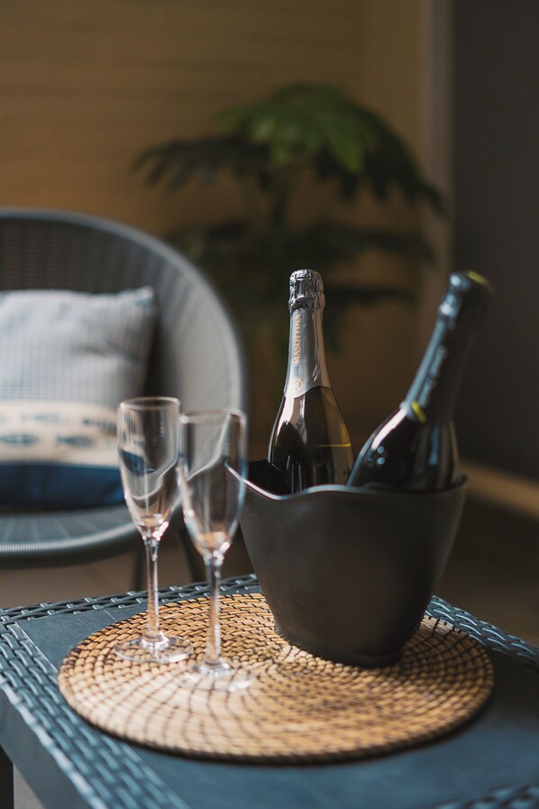 Una mesa con una botella de champán y dos copas sobre un mantel tejido.