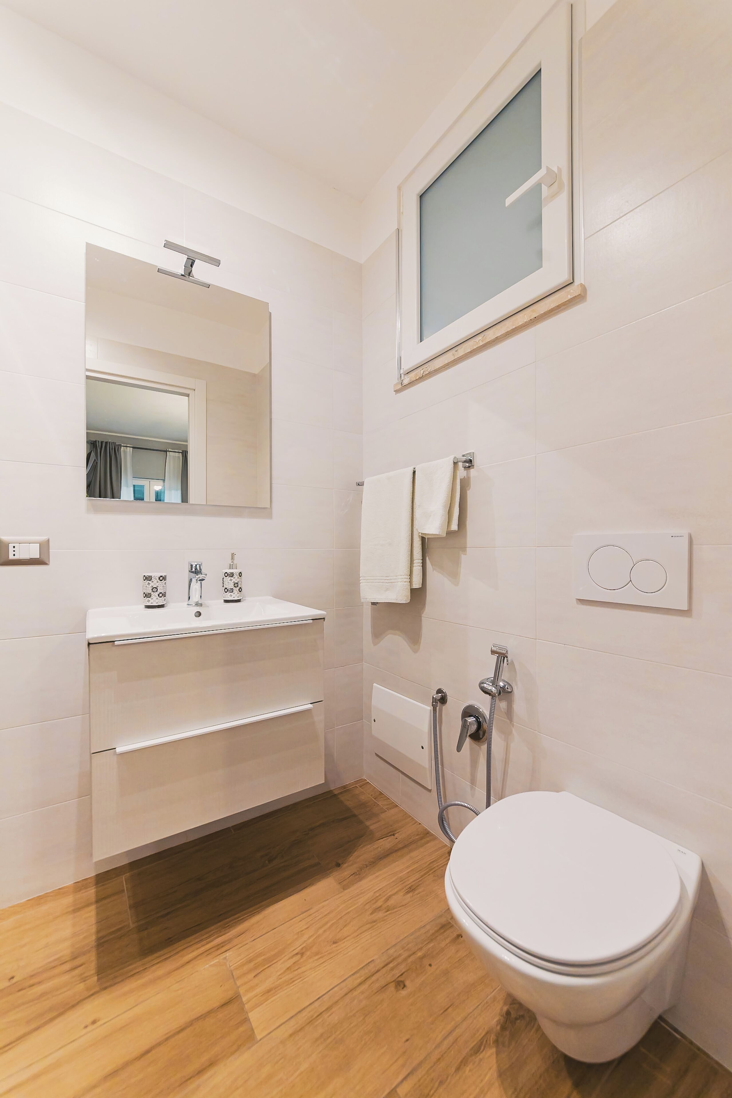 A modern bathroom with a white sink, mirror, and toilet.