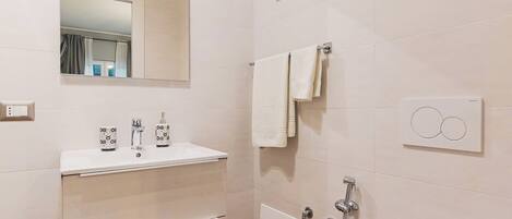 A modern bathroom with a white sink, mirror, and toilet.