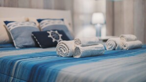 Un letto rifatto con lenzuola blu e asciugamani bianchi arrotolati.